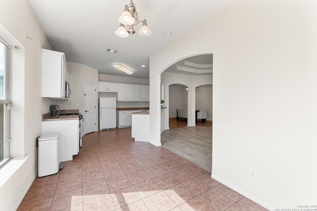 7619 Bit Cir, Elmendorf, TX 78112 - kitchen featuring appliances with stainless steel finishes, arched walkways, a chandelier, white cabinets, and baseboards