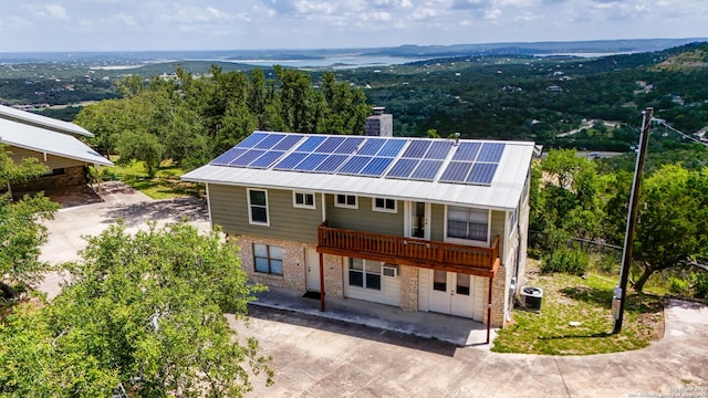 1001 Naked Indian, New Braunfels, TX 78132 - back of property featuring central AC unit, roof mounted solar panels, concrete driveway, a chimney, and stone siding