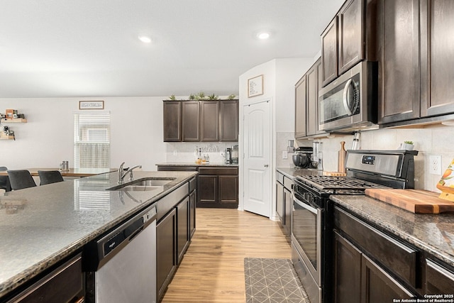 6417 Hoffman Pln, San Antonio, TX 78252 - kitchen with appliances with stainless steel finishes, a sink, dark brown cabinets, light wood-style floors, and decorative backsplash