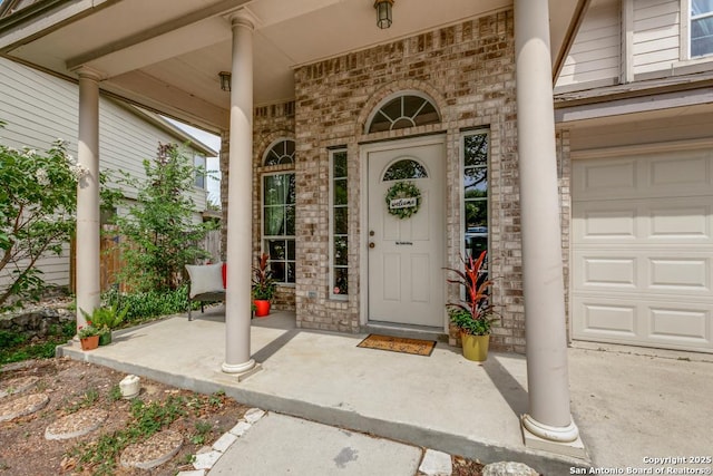 8227 Maloy Mnr, San Antonio, TX 78250 - view of exterior entry with a porch, brick siding, and a garage