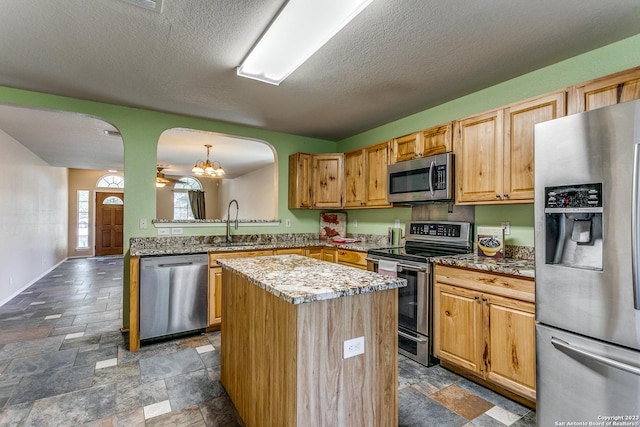 8227 Maloy Mnr, San Antonio, TX 78250 - kitchen featuring stainless steel appliances, arched walkways, a kitchen island, a sink, and dark stone finish flooring