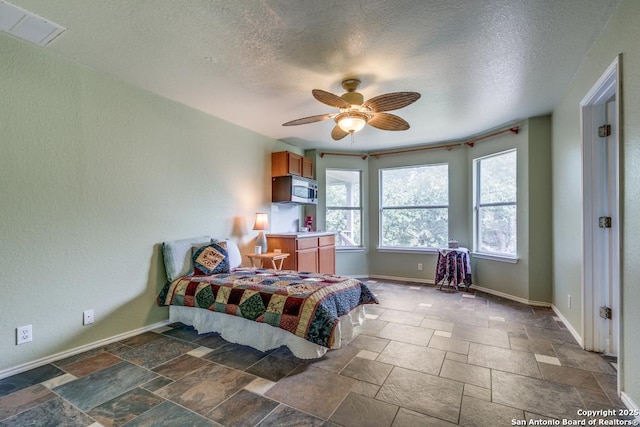 8227 Maloy Mnr, San Antonio, TX 78250 - bedroom featuring stone tile flooring, a textured ceiling, and baseboards