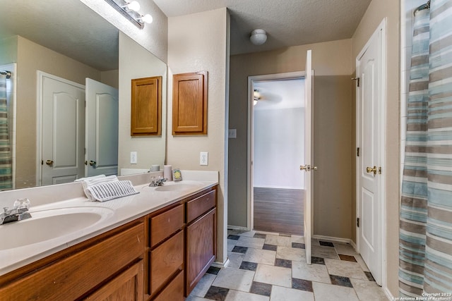 8227 Maloy Mnr, San Antonio, TX 78250 - bathroom with double vanity, baseboards, and a textured ceiling