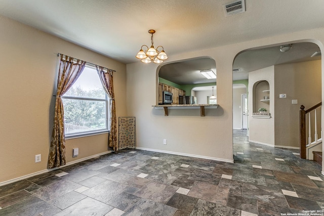 8227 Maloy Mnr, San Antonio, TX 78250 - unfurnished room featuring arched walkways, baseboards, stone tile floors, stairway, and a chandelier