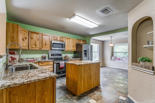 8227 Maloy Mnr, San Antonio, TX 78250 - kitchen featuring appliances with stainless steel finishes, a sink, stone tile flooring, a center island, and light stone counters