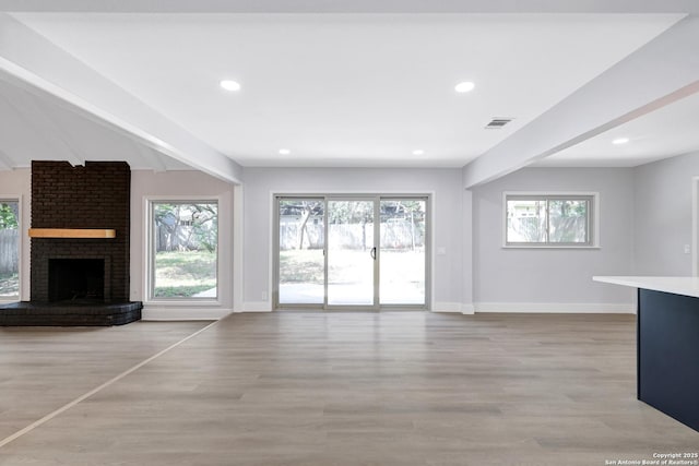5411 Lancashire, San Antonio, TX 78230 - unfurnished living room featuring beam ceiling, baseboards, healthy amount of natural light, light wood finished floors, and a fireplace
