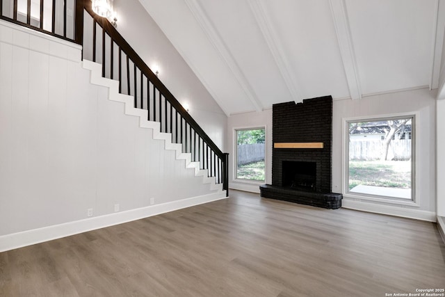 5411 Lancashire, San Antonio, TX 78230 - unfurnished living room with beam ceiling, stairs, wood finished floors, a brick fireplace, and high vaulted ceiling