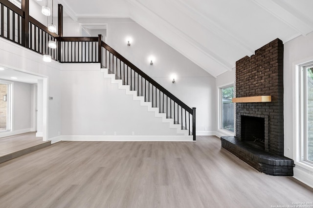 5411 Lancashire, San Antonio, TX 78230 - unfurnished living room with beam ceiling, wood finished floors, high vaulted ceiling, stairway, and a brick fireplace