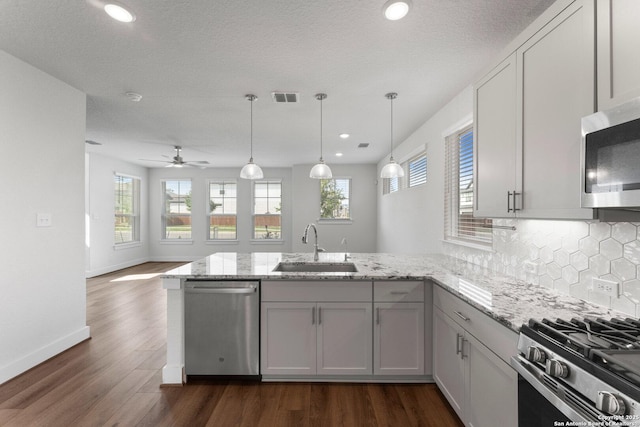 9607 Stillwater Pass, San Antonio, TX 78254 - kitchen featuring stainless steel appliances, a sink, a peninsula, backsplash, and dark wood finished floors