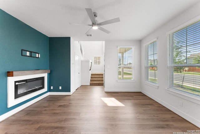 9607 Stillwater Pass, San Antonio, TX 78254 - unfurnished living room featuring a glass covered fireplace, ceiling fan, wood finished floors, and stairway