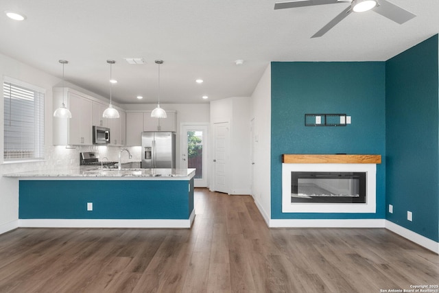 9607 Stillwater Pass, San Antonio, TX 78254 - kitchen with stainless steel appliances, a peninsula, wood finished floors, ceiling fan, and light countertops