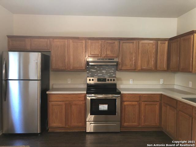 5514 Justin, San Antonio, TX 78240 - kitchen featuring stainless steel appliances, under cabinet range hood, light countertops, dark wood-style flooring, and brown cabinets
