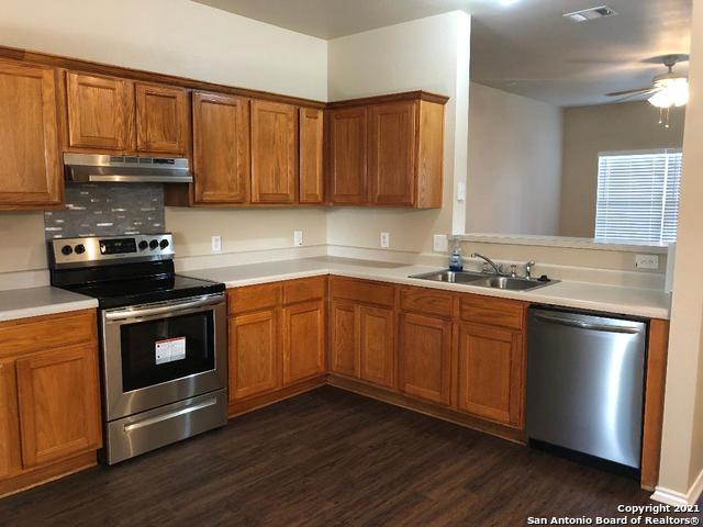 5514 Justin, San Antonio, TX 78240 - kitchen with appliances with stainless steel finishes, under cabinet range hood, a sink, dark wood finished floors, and brown cabinetry