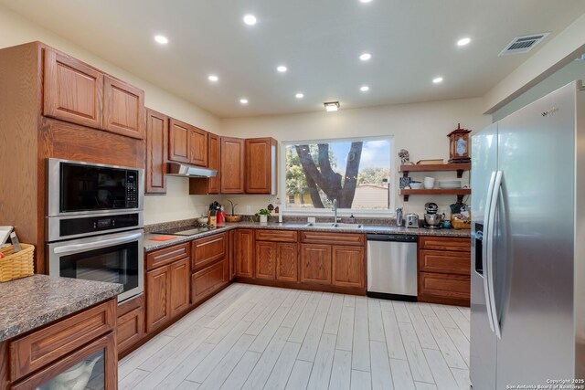 246 Felisa St, San Antonio, TX 78210 - kitchen with black appliances, a sink, under cabinet range hood, brown cabinets, and light wood finished floors