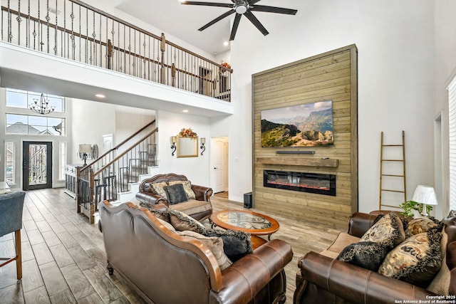 14042 Gemma, San Antonio, TX 78253 - living room featuring a towering ceiling, a glass covered fireplace, stairs, ceiling fan, and a chandelier