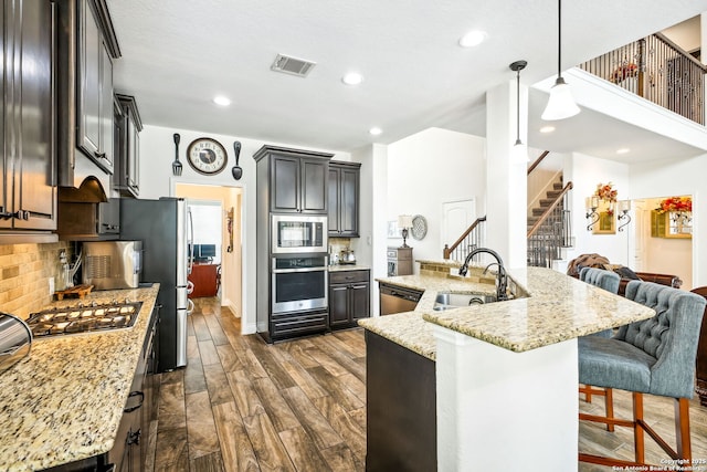 14042 Gemma, San Antonio, TX 78253 - kitchen with stainless steel appliances, a sink, dark wood-style floors, a breakfast bar, and light stone counters