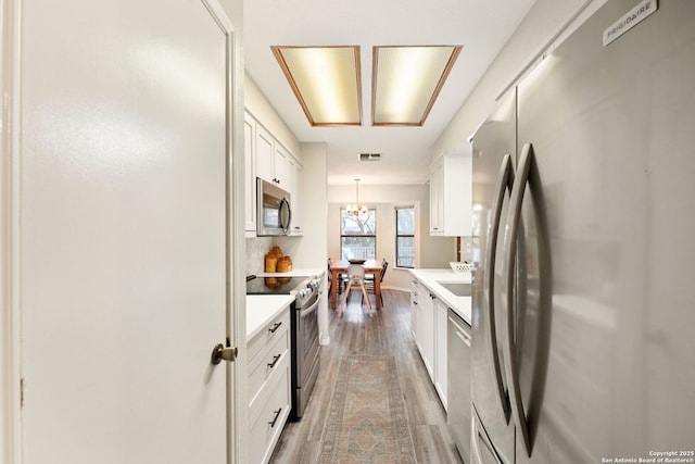 5535 Timber Cyn, San Antonio, TX 78250 - kitchen featuring stainless steel appliances, light wood-type flooring, white cabinets, light countertops, and pendant lighting
