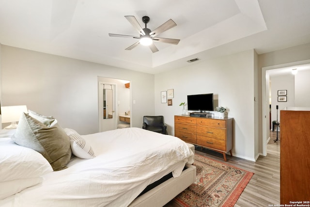 5535 Timber Cyn, San Antonio, TX 78250 - bedroom featuring a tray ceiling, light wood-type flooring, baseboards, ceiling fan, and ensuite bathroom