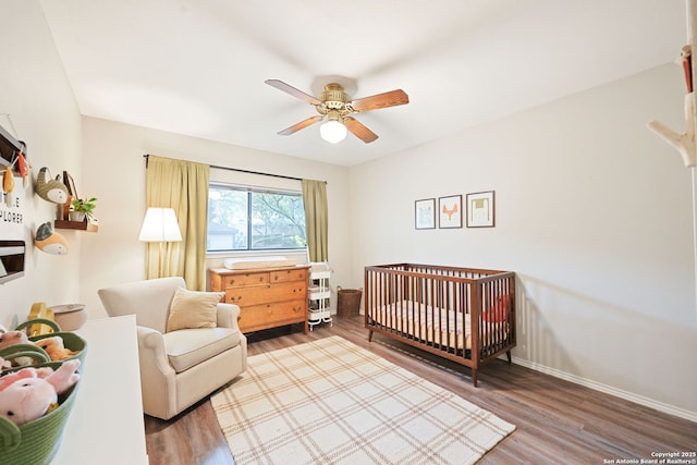 5535 Timber Cyn, San Antonio, TX 78250 - bedroom featuring wood finished floors, baseboards, a crib, and a ceiling fan