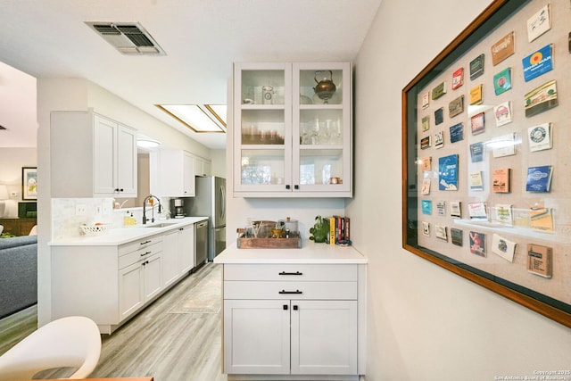5535 Timber Cyn, San Antonio, TX 78250 - kitchen with stainless steel appliances, a sink, glass insert cabinets, light countertops, and white cabinets