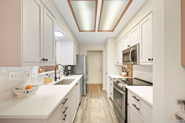 5535 Timber Cyn, San Antonio, TX 78250 - kitchen featuring appliances with stainless steel finishes, a sink, light wood-style flooring, backsplash, and light countertops