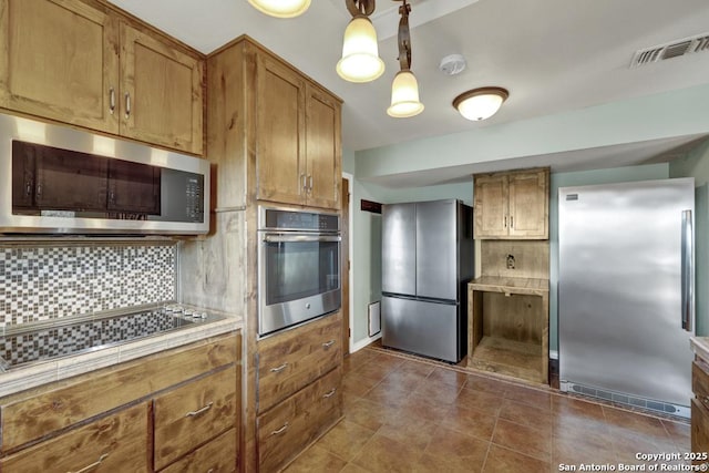 642 Lakebreeze, Canyon Lake, TX 78133 - kitchen with appliances with stainless steel finishes, tasteful backsplash, brown cabinets, tile countertops, and dark tile patterned floors