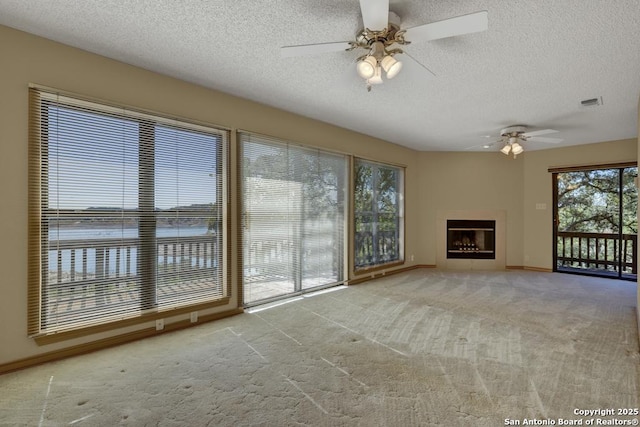 642 Lakebreeze, Canyon Lake, TX 78133 - unfurnished living room with a textured ceiling, a ceiling fan, carpet floors, and a fireplace