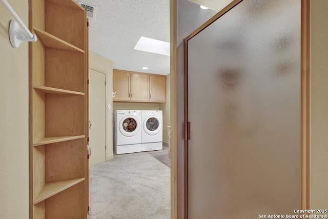 642 Lakebreeze, Canyon Lake, TX 78133 - washroom featuring a skylight, separate washer and dryer, cabinet space, light carpet, and a textured ceiling