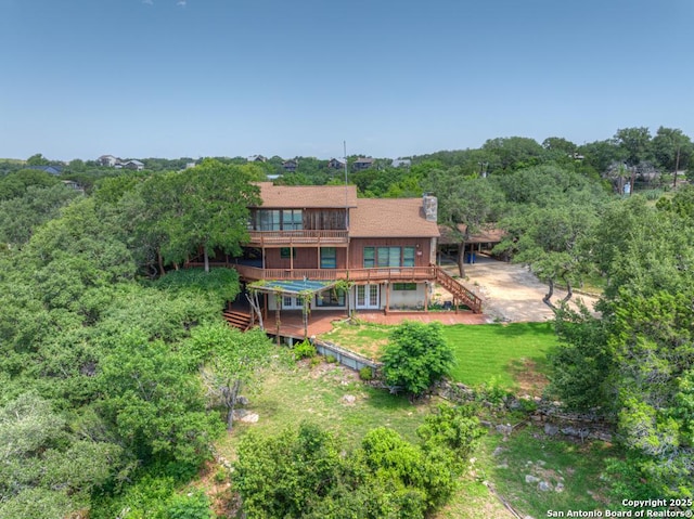 642 Lakebreeze, Canyon Lake, TX 78133 - back of house with stairway, a wooden deck, a chimney, a wooded view, and a yard