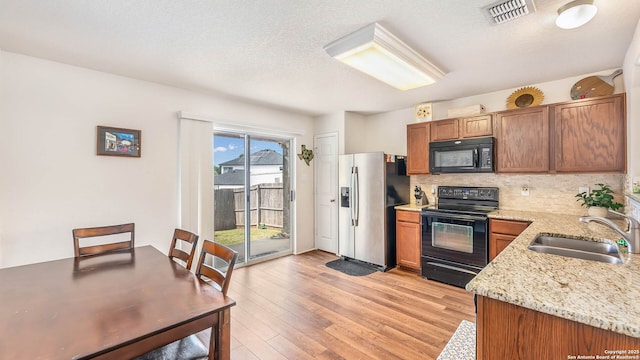 3714 Hideaway Grn, San Antonio, TX 78261 - kitchen featuring black appliances, a sink, tasteful backsplash, light wood finished floors, and light stone countertops