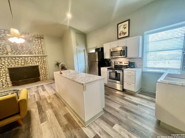 415 Fort Clark Rd Unit 21, Brackettville, TX 78832 - kitchen with stainless steel appliances, vaulted ceiling, a sink, light wood finished floors, and white cabinetry