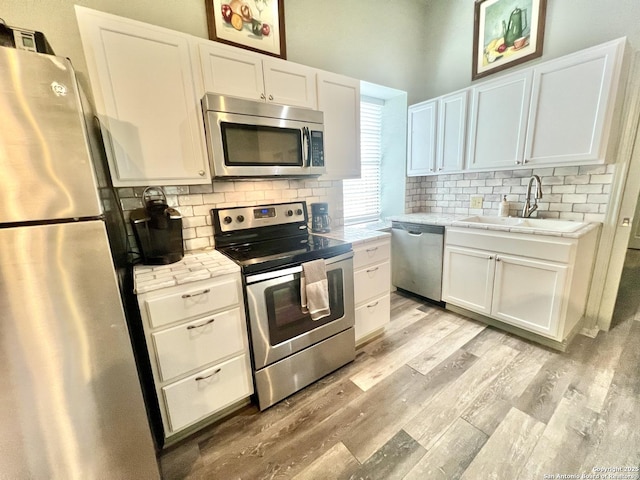 415 Fort Clark Rd Unit 21, Brackettville, TX 78832 - kitchen featuring appliances with stainless steel finishes, a sink, light wood-type flooring, white cabinetry, and backsplash