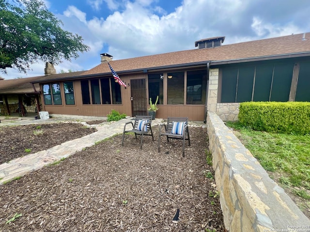415 Fort Clark Rd Unit 21, Brackettville, TX 78832 - rear view of property with a patio area, stone siding, a shingled roof, and a chimney