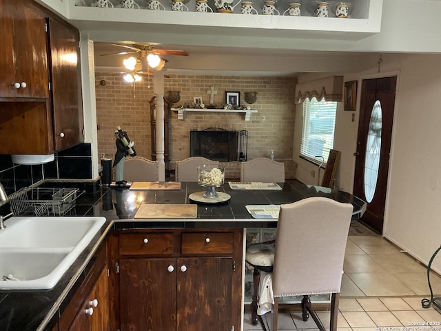 2918 Hatton, San Antonio, TX 78237 - kitchen featuring a sink, light tile patterned flooring, a ceiling fan, a peninsula, and a brick fireplace