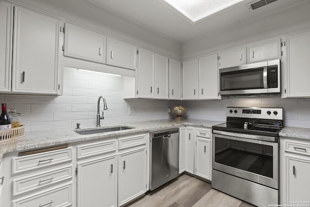 3105 Pecan Valley Dr, Temple, TX 76502 - kitchen featuring appliances with stainless steel finishes, a sink, light wood-style floors, and white cabinets