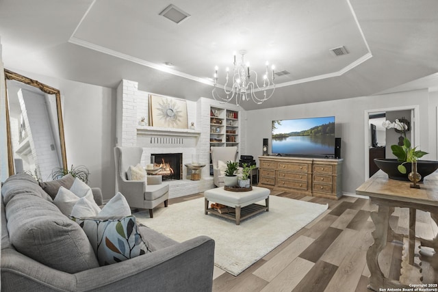3105 Pecan Valley Dr, Temple, TX 76502 - living area with a tray ceiling, wood finished floors, a chandelier, a fireplace, and built in shelves