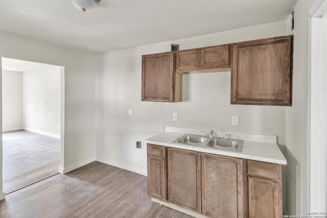 2338 Burnet, San Antonio, TX 78202 - kitchen with a sink, light countertops, light wood-style flooring, brown cabinets, and a textured ceiling