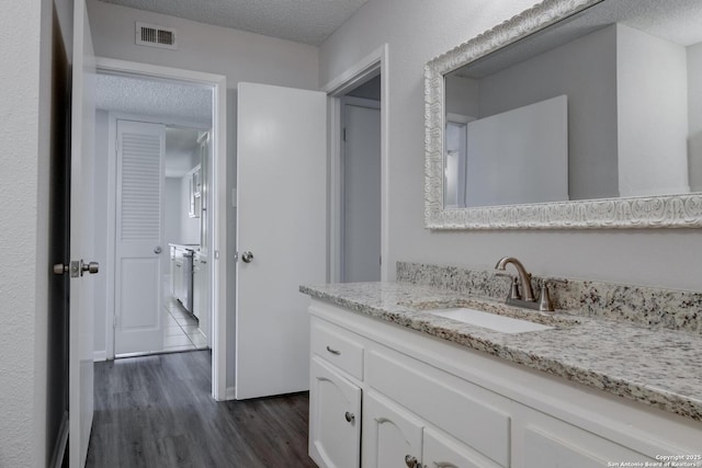 8915 Datapoint Unit 49A, San Antonio, TX 78229 - bathroom with a textured ceiling, wood finished floors, and vanity