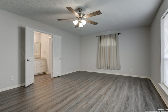 8915 Datapoint Unit 49A, San Antonio, TX 78229 - unfurnished bedroom with dark wood-style floors, baseboards, ensuite bathroom, multiple windows, and a textured ceiling