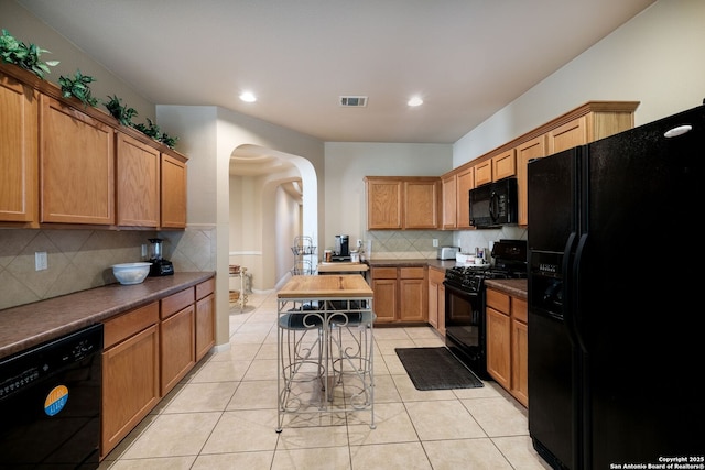 20710 Meandering Cir, San Antonio, TX 78258 - kitchen featuring black appliances, arched walkways, backsplash, dark countertops, and light tile patterned floors