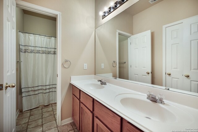 20710 Meandering Cir, San Antonio, TX 78258 - full bathroom featuring double vanity, baseboards, stone finish floors, and a shower with shower curtain