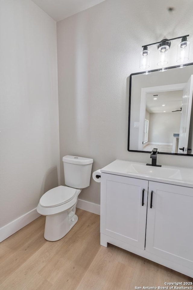 907 Amigo, San Antonio, TX 78260 - half bathroom with wood finished floors, toilet, baseboards, and vanity