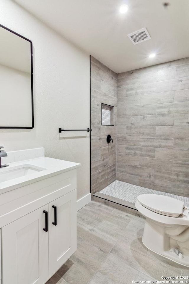 907 Amigo, San Antonio, TX 78260 - bathroom with vanity, a tile shower, toilet, recessed lighting, and baseboards