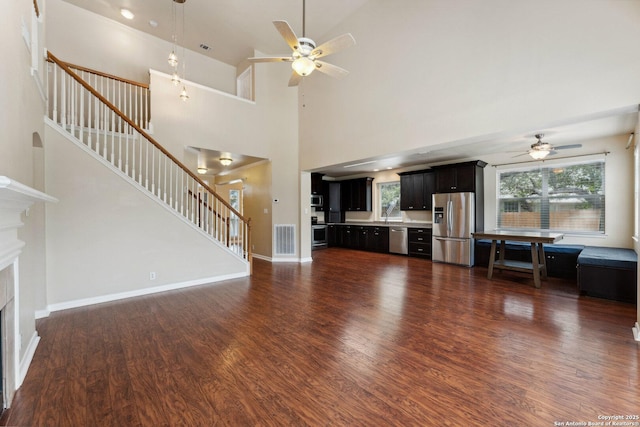 5914 Hart Fld, San Antonio, TX 78249 - unfurnished living room with a ceiling fan, a fireplace, dark wood-style floors, stairway, and a towering ceiling