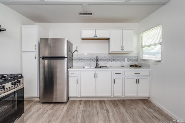 326 Sublett, San Antonio, TX 78223 - kitchen with stainless steel appliances, a sink, white cabinetry, light countertops, and light wood-type flooring