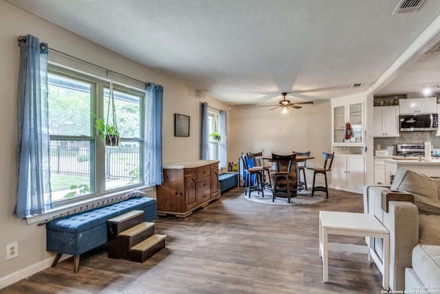 6034 Royal, San Antonio, TX 78239 - living area with a ceiling fan, dark wood-style flooring, baseboards, and a textured ceiling