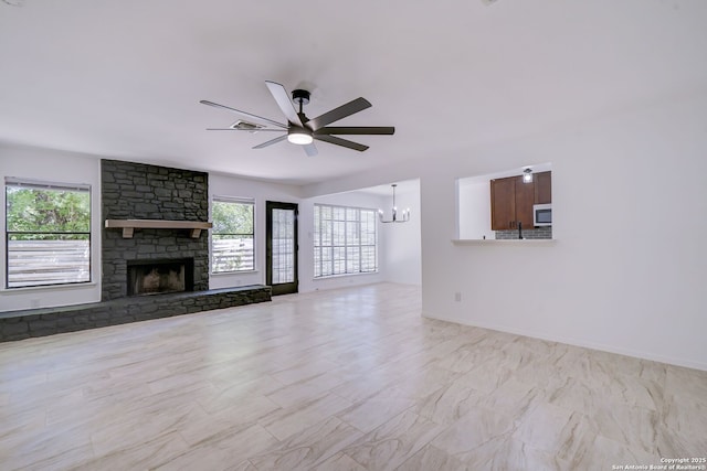 3250 Bear Spgs, San Antonio, TX 78245 - unfurnished living room featuring a chandelier, ceiling fan, and a stone fireplace