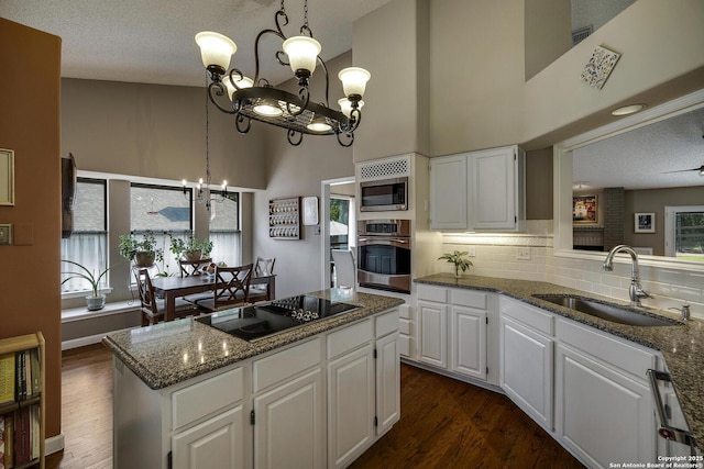 7011 Washita Way, San Antonio, TX 78256 - kitchen featuring appliances with stainless steel finishes, a sink, a chandelier, a high ceiling, and dark stone countertops