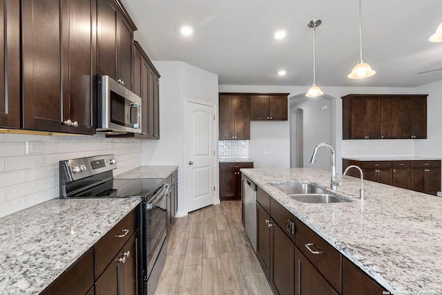 164 Antler Bnd, San Antonio, TX 78253 - kitchen featuring stainless steel appliances, decorative backsplash, light stone counters, hanging light fixtures, and dark brown cabinets