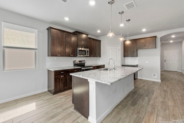 164 Antler Bnd, San Antonio, TX 78253 - kitchen featuring stainless steel appliances, arched walkways, light wood finished floors, backsplash, and light stone countertops